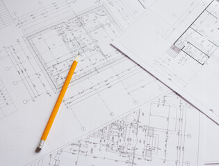 pencil and office tools for writing on the blueprint of construction industry. Place the rolls on a desk over blurred blueprint for construction industry background.