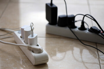 Overloaded power boards. Power strips with different electrical plugs on white floor. Concept of...