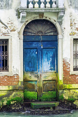 blaue Holztür eines alten Hauses direkt am Wasser Kanal von Venedig