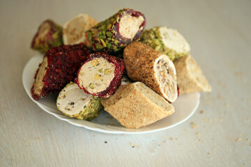 Many rolls of turkish delight with different flavors and fillings in white plate on table. Cuts of Turk Lokumu sweets