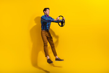 Full size photo of funny positive guy dressed striped shirt hold steering wheel look empty space...