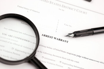 District Court Arrest Warrant court papers on A4 tablet lies on office table with pen and...