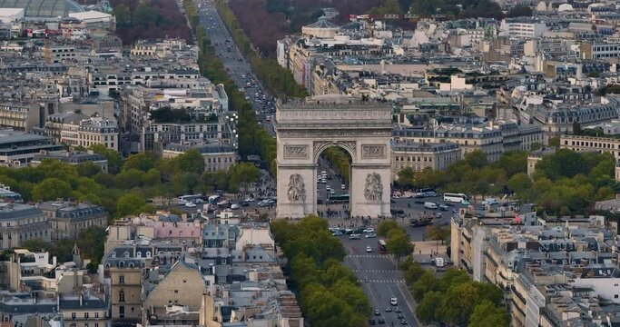 Establishing shot of the streets of Paris in the summer. Drone shot of french streets are full of cars and people. Aerial view, above trees and traffic, surrounded by french buildings and architecture