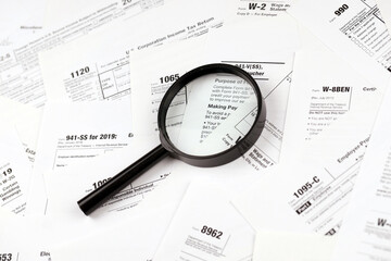 Magnifying glass lying over heap of paper documents. Investigation and financial audit concept