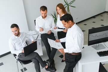Team of brokers is working in office using workstation and analysis technology.