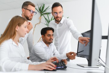 Obraz premium Happy businesspeople laughing while collaborating on a new project in an office. Group of diverse businesspeople working together in a modern workspace
