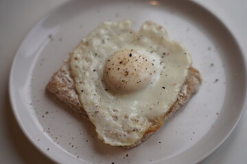 Close up of a fried eggs in a white plate at the kitchen table.