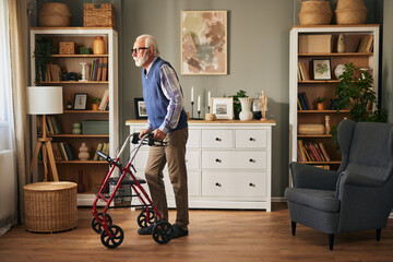 Senior man with disability using walker assistance at home