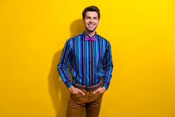 Photo of confident gentleman dressed striped shirt tie bow standing hold arms in pockets isolated on vivid yellow color background