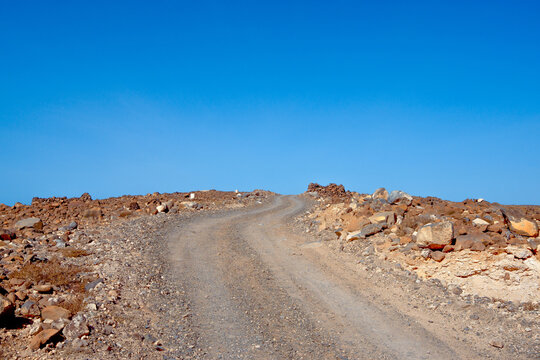 Schotterstra&szlig;e die auf ein Berg f&uuml;hrt mit Steinen und Felsen an Wegesrand