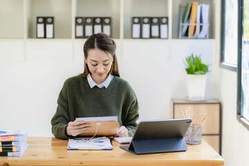 Professional business woman, corporate marketing manager, female worker holding a digital tablet is reading information of a new startup on the tablet and analyzing business strategy and planning.