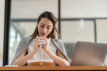 Asian businesswoman working hard in the office, stressed and tired with paperwork and digging her hand from work errors.