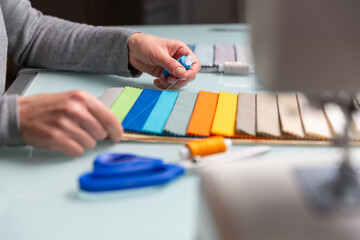 Tailor choosing right color of a blue thread using fabric samples on table during sewing process - 685684235