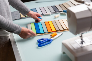 Tailor choosing right color of a blue thread using fabric samples on table during sewing process - 685684248