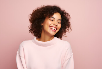 Young glad woman points at toothy smile shows perfect white teeth being in good mood keeps eyes closed dressed in casual knitted jumper isolated over pink background. 