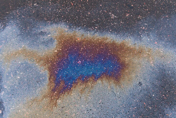 Textured stain of fuel or oil on wet asphalt on a rainy day.