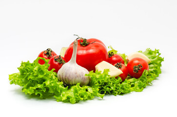 Mix of fresh vegetables - garlic, tomatoes and green salad leaves. White background, isolated..