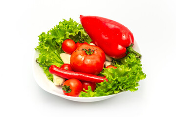 Mix of fresh vegetables - bell peppers and chilies, garlic, tomatoes, green salad in a white bowl.