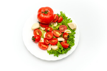 White plate of salad with vegetables on white background. Top view. Tomato, pepper, salad, garlic.