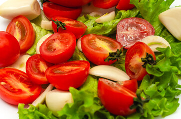 Mix of fresh vegetables - garlic, tomatoes and green salad leaves. White background, isolated..
