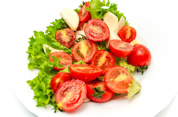 Delicious vegetable salad in a bowl on a white background. Chopped tomatoes, lettuce, garlic, salt.