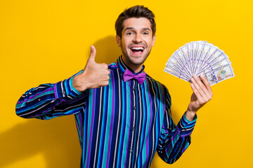 Photo of optimistic positive man dressed striped shirt bow tie hold money showing thumb up good job...