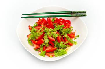 White plate of salad with vegetables isolated on white background. Wooden chopsticks for food.