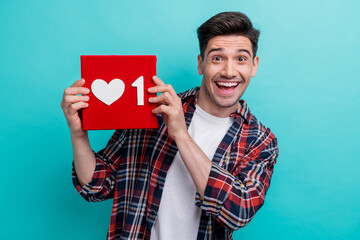 Photo of excited funky guy wear checkered shirt rising positive feedback heart isolated teal color...