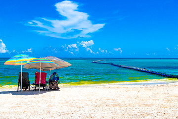 Tropical Caribbean beach people parasols fun Playa del Carmen Mexico.