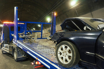 Tow truck loading a crashed car. Crumpled bumper.