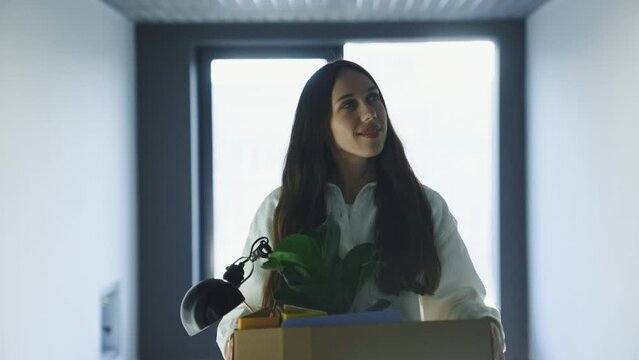 A new office worker with a box in his hands goes to the office. The first working day in a new place