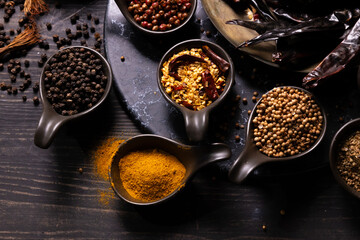 Various type of oriental earthy flavor dry spices on dark wooden table such as black pepper,...