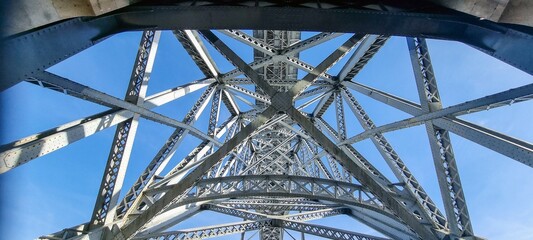 Photo of a structure of steel girders of a bridge in front of a blue sky