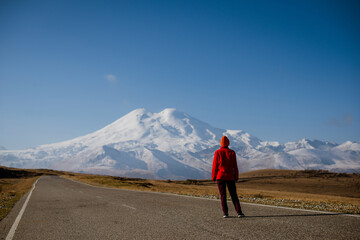the girl stands on the road and looks at Elbrus