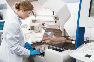 female scientist working in a modern equipped computer laboratory analyzes blood samples and...
