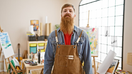 Serious young redhead man artist, master of the paintbrush, standing indoors at the university art...