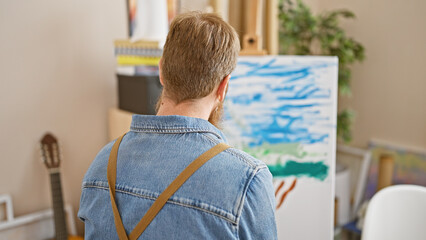 Handsome young redhead man, an ambitious artist, immerse in drawing at the interior art studio,...