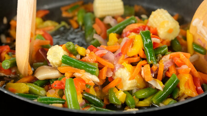 Frying in pan vegetables green beans, tomatoes, bell peppers
