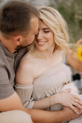 Beautiful pregnant couple in love spending time together in nature at sunset, having a picnic.