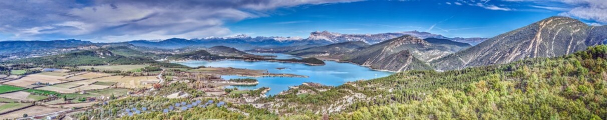 Drone panorama over the Mediano reservoir in the Spanish Pyrenees with snow-covered mountains in the background