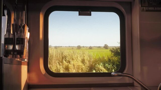 Window View Train Travelling Countryside Sunny Day Vehicle Shot. Window view from a train traveling across the countryside, empty car. Vehicle shot