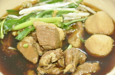 braised pork tendon and meatball with bean sprout in brown soup on bowl 
