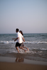 A man and a woman running along the seashore, Sunset scene. Couple in love, happy couple. Valentine's Day, sstkLOVE