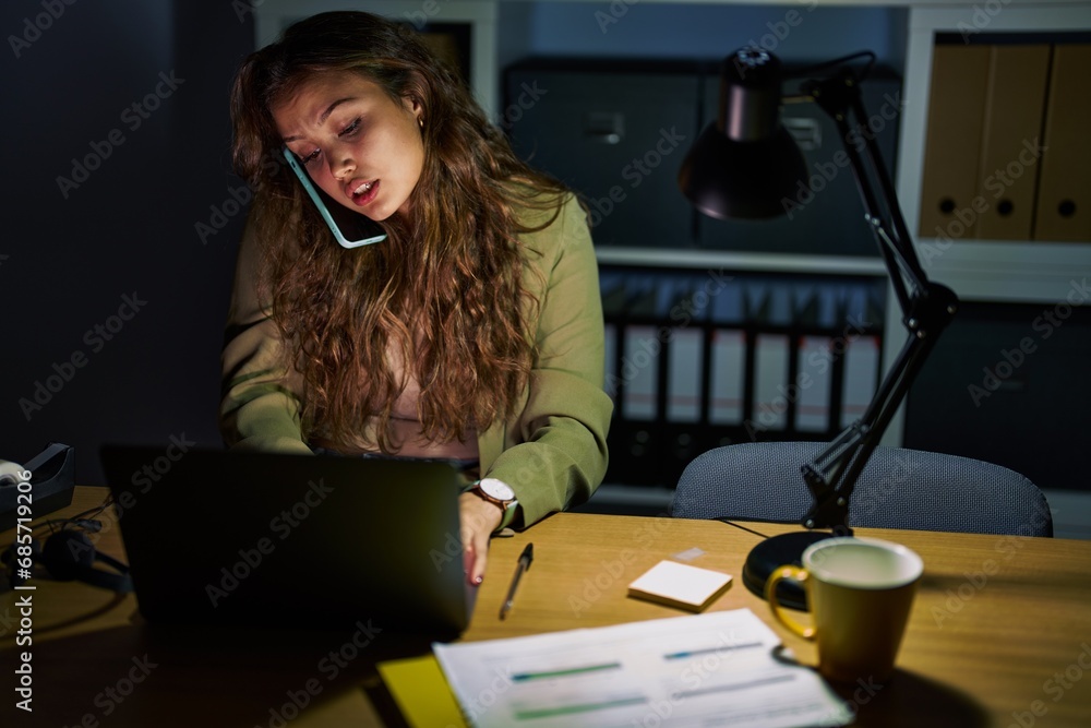 Canvas Prints Young beautiful hispanic woman business worker using laptop talking on smartphone at office