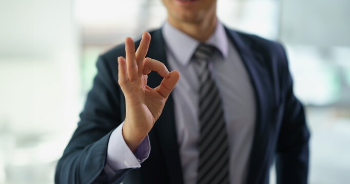 Businessman in suit showing hand gesture ok at work in office closeup. Approve good choice concept