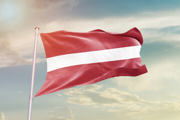 Latvia national flag waving in beautiful sky. The symbol of the state on wavy silk fabric.