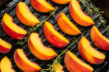 Sweet and juicy roasted peaches on a a grill pan on a dark background. top view