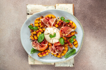 Heathy summer salad with grilled peach, ham and burrata on a dark background. top view. copy space for text