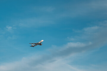 Airplane flies gaining altitude in blue sky in prescribed direction