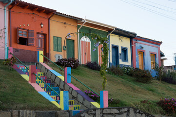 Colorful houses on a grassy hill accessed by stairs with a small portal at the beginning